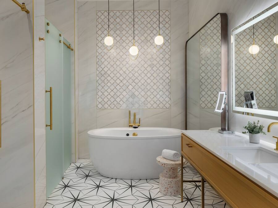 A modern bathroom with a freestanding bathtub, a vanity with a mirror, and a geometric-patterned floor.