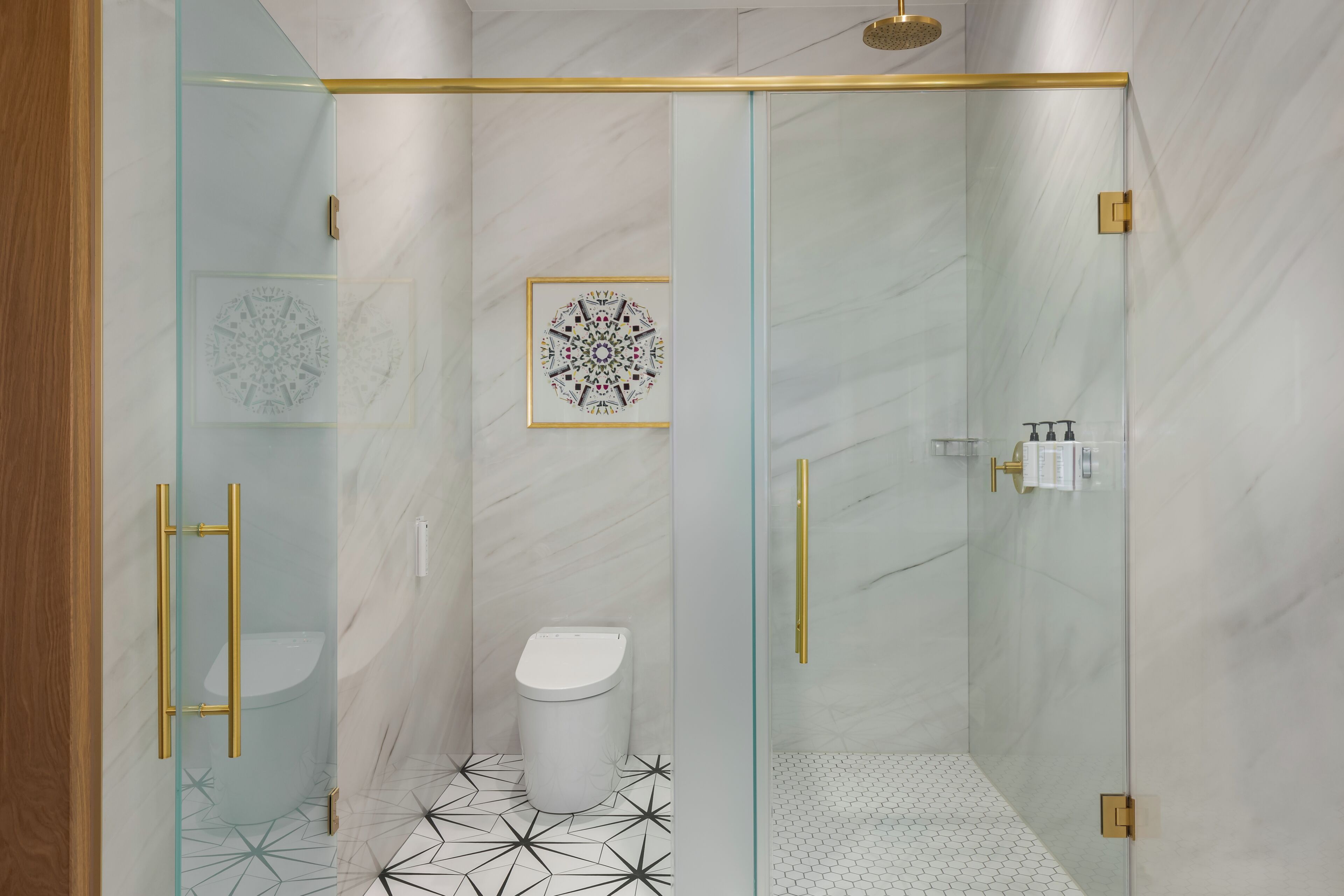 A modern bathroom with a glass-enclosed shower, a toilet, and a sink.