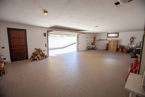 Eine geräumige Garage mit Fliesenboden, einer Holztür und einem Fahrrad.