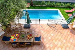 A poolside area with a dining table, chairs, and a pool.