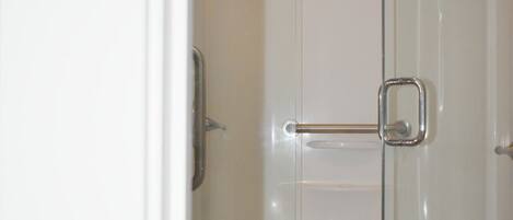 A glass-enclosed shower with a toilet visible in the adjacent room.