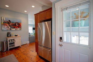 A kitchen with a stainless steel refrigerator, wooden cabinets, a coffee maker, and a painting on the wall.
