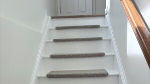 A staircase with carpeted steps and a wooden handrail. - Luxury Waterfront Oasis with Pool & Beach Access (Ocean City)