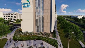 Un edificio moderno de Advent Health con una entrada destacada, estacionamiento accesible y un área ajardinada con árboles y un sendero.