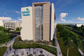 A modern Advent Health building with a prominent entrance, accessible parking, and a landscaped area with trees and a pathway.
