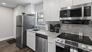 Una cocina moderna con electrodomésticos de acero inoxidable, encimera de granito y armarios blancos.