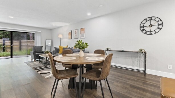 Un comedor moderno con una mesa redonda, sillas y un reloj colgado en la pared.