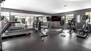 Un gimnasio moderno con cintas de correr, máquinas de pesas y un espejo grande.