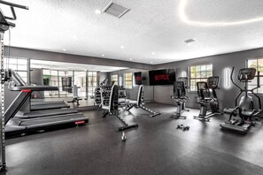 A modern gym with treadmills, weight machines, and a large mirror.