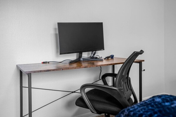 Un espace de travail comprenant un bureau, un écran d’ordinateur et une chaise.