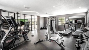 Et moderne fitnesscenter med forskellig træningsudstyr, store vinduer og en ren, rummelig indretning.