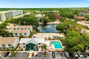 An aerial view of a hotel with a swimming pool, a parking lot, and a river in the background.