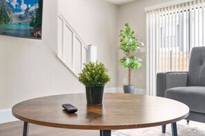 A round wooden table with a potted plant and a remote control.