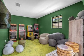 Ein Zimmer mit grünen Wänden, vier Spielautomaten, einem großen Fenster und einem grünen Teppich.