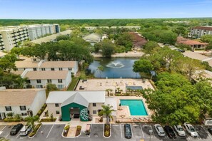 A hotel with a swimming pool, a parking lot, and a view of a river.
