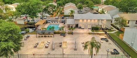 Vista aérea de una zona residencial con piscina, sillas de descanso y un patio vallado.