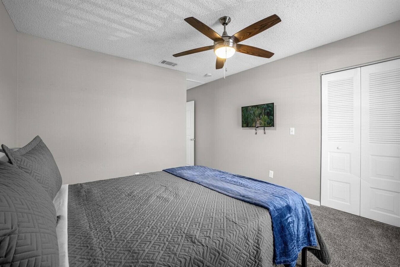 Une chambre à coucher avec un lit, un ventilateur de plafond, une porte et un placard.