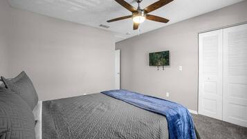 Une chambre à coucher avec un lit, un ventilateur de plafond, une porte et un placard.