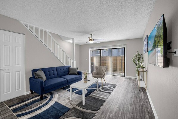 A modern living room with a blue sofa, a white coffee table, and a grey armchair.