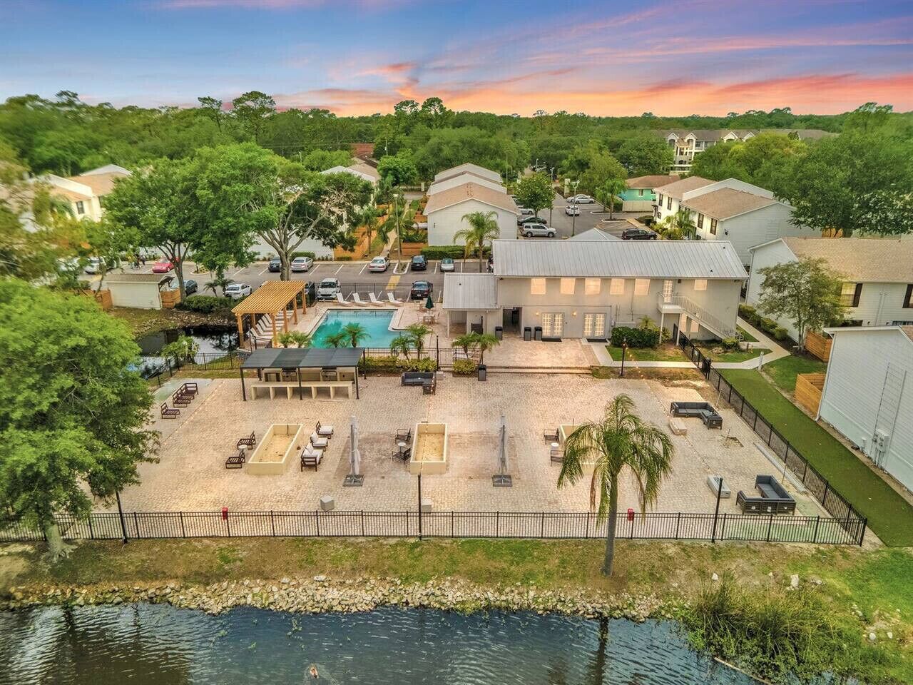 Zona residencial con piscina, mobiliario exterior y un muelle junto al agua.