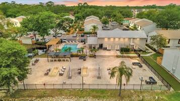 Zona residencial con piscina, mobiliario exterior y un muelle junto al agua.