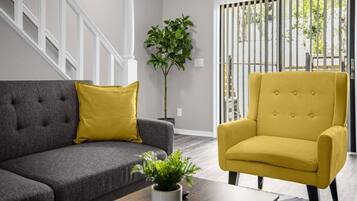 A living room with a grey sofa, a yellow armchair, and a potted plant on a wooden coffee table.