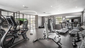 Une salle de sport moderne équipée de machines de cardio, de matériel de musculation et d’un grand miroir.