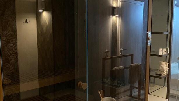 A modern bathroom with a glass partition, wooden flooring, and a shower area.