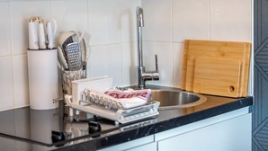Een moderne keuken met een RVS spoelbak, een houten snijplank, een rasp en een afdruiprek met handdoeken.
