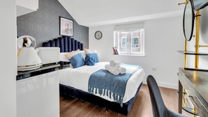 Een moderne slaapkamer met een bed, nachtkastje en bureau met stoel.