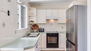 Een functionele keuken met een roestvrijstalen koelkast, een inbouwoven, een broodrooster en een spoelbak.