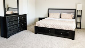 Ein Schlafzimmer mit Bett, Schminktisch, Nachttisch, Deckenventilator und Spiegel.