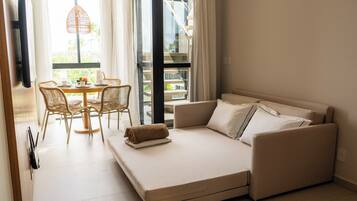 Una habitación moderna con una cama sofá, una mesa de comedor con sillas y vistas a un edificio.
