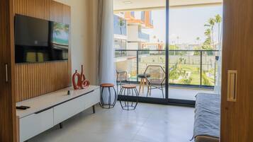 Una habitación de hotel moderna con una tele grande, un balcón con sillas y una cama.