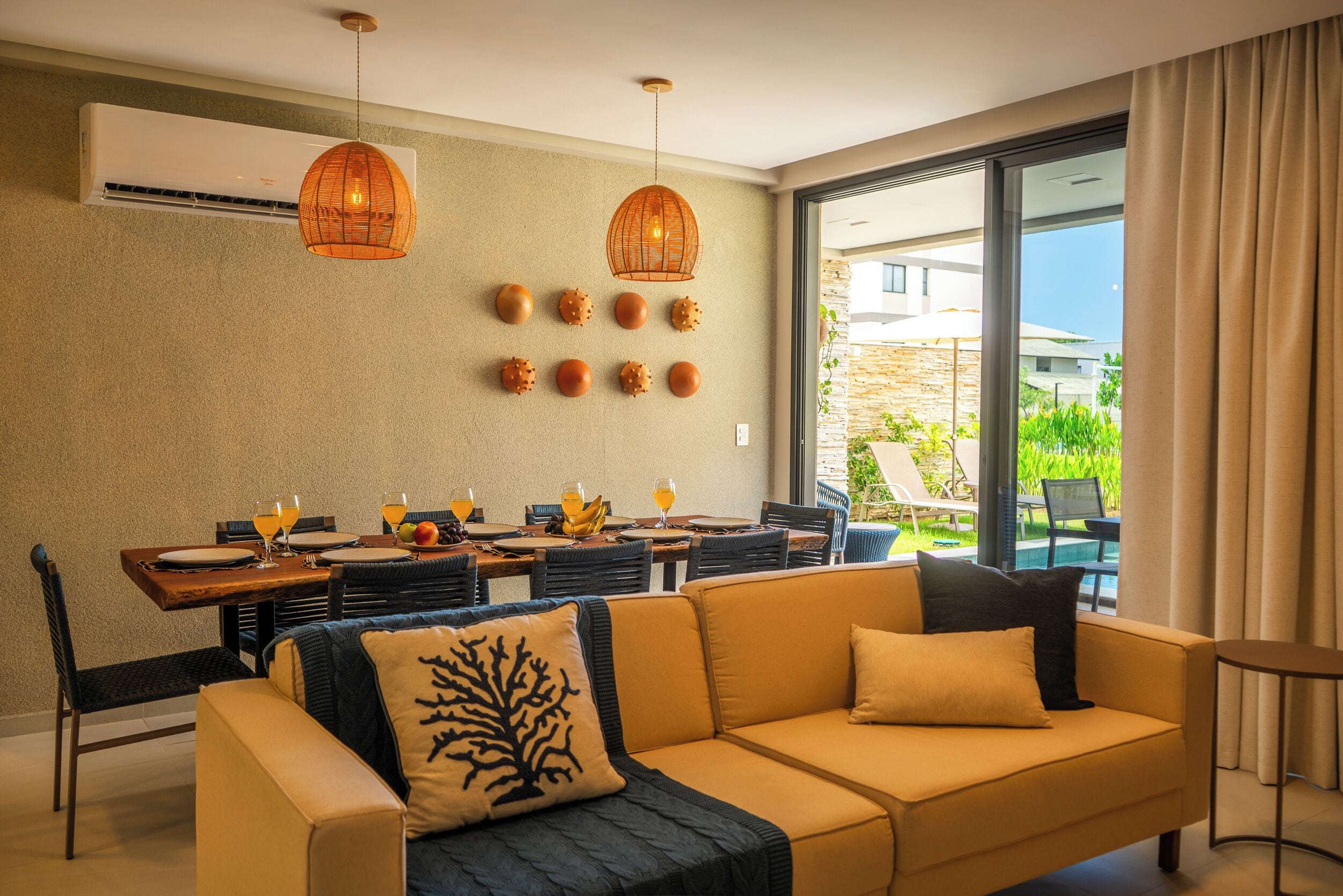 Una sala de estar moderna con un sofá, una mesa de comedor y sillas. Hay un ventanal con vistas al exterior.