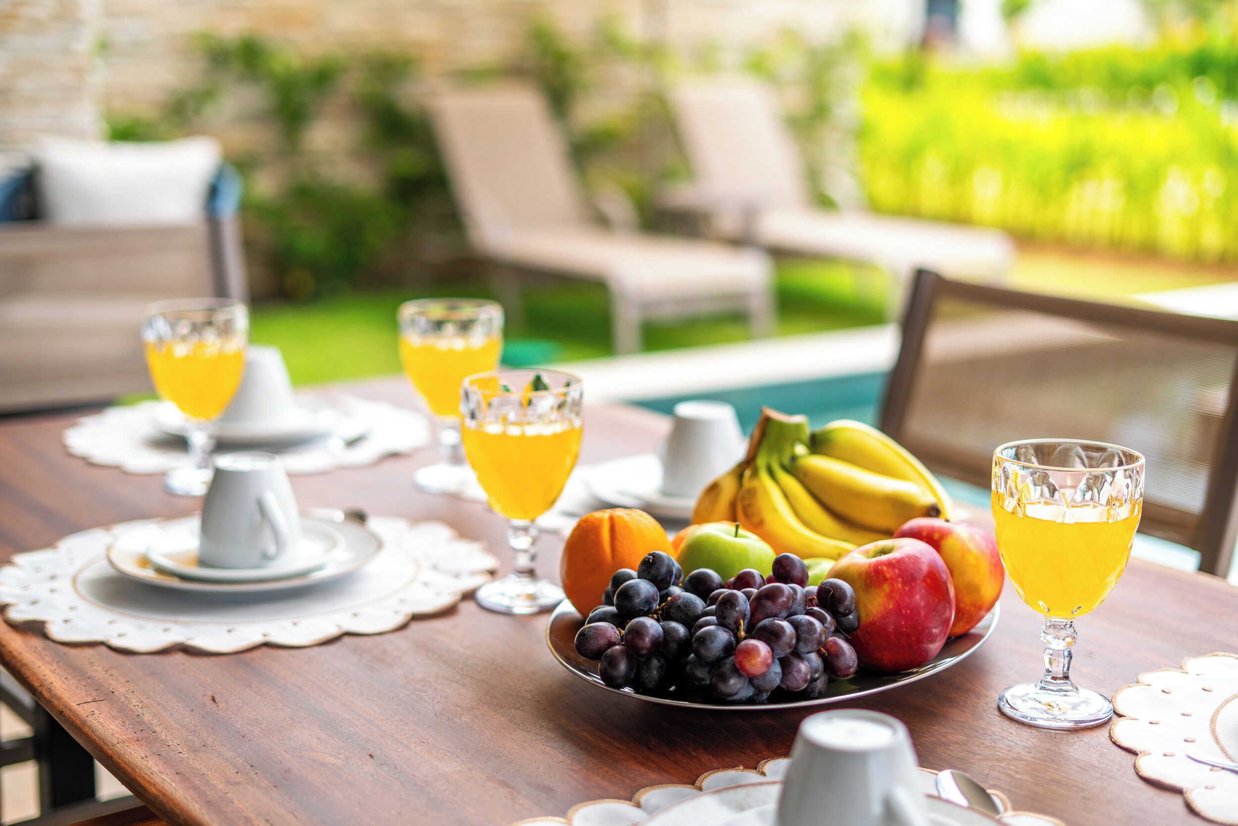 A dining table with a fruit bowl, glasses of orange juice, and a pitcher.