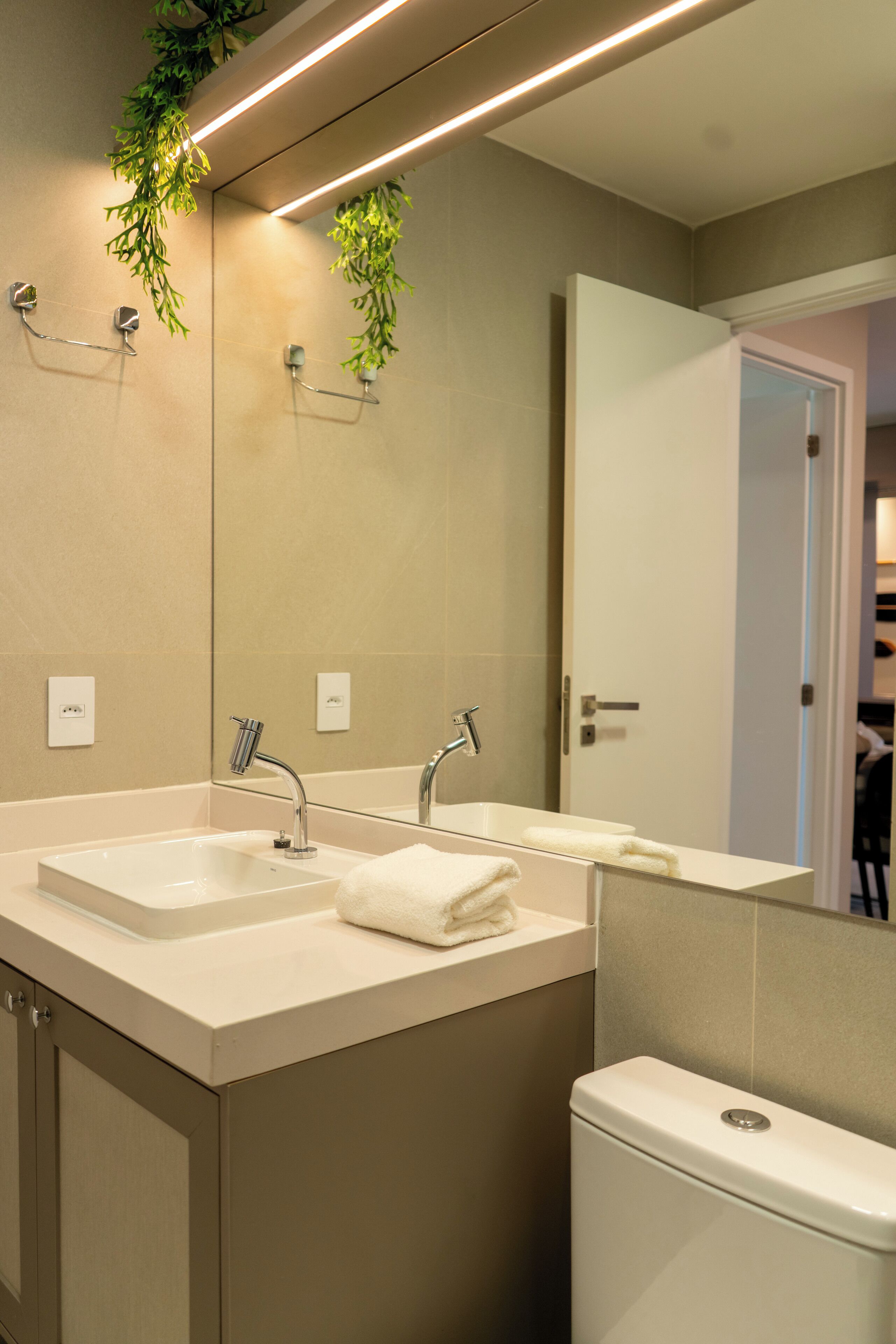 A modern bathroom with two sinks, a toilet, and a large mirror.