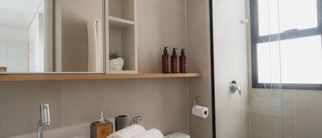 Un bagno moderno con lavandino, toilette e doccia. Sono presenti asciugamani, articoli da toilette e uno specchio.
