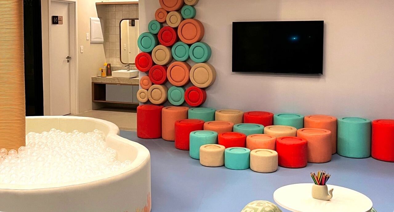 Un baño moderno con una bañera grande llena de burbujas, un televisor montado en la pared y una colorida disposición de jabones.
