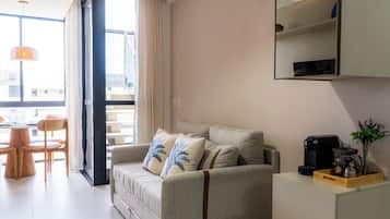 Una sala de estar moderna con un sofá, una cafetera y un comedor con sillas y una mesa.
