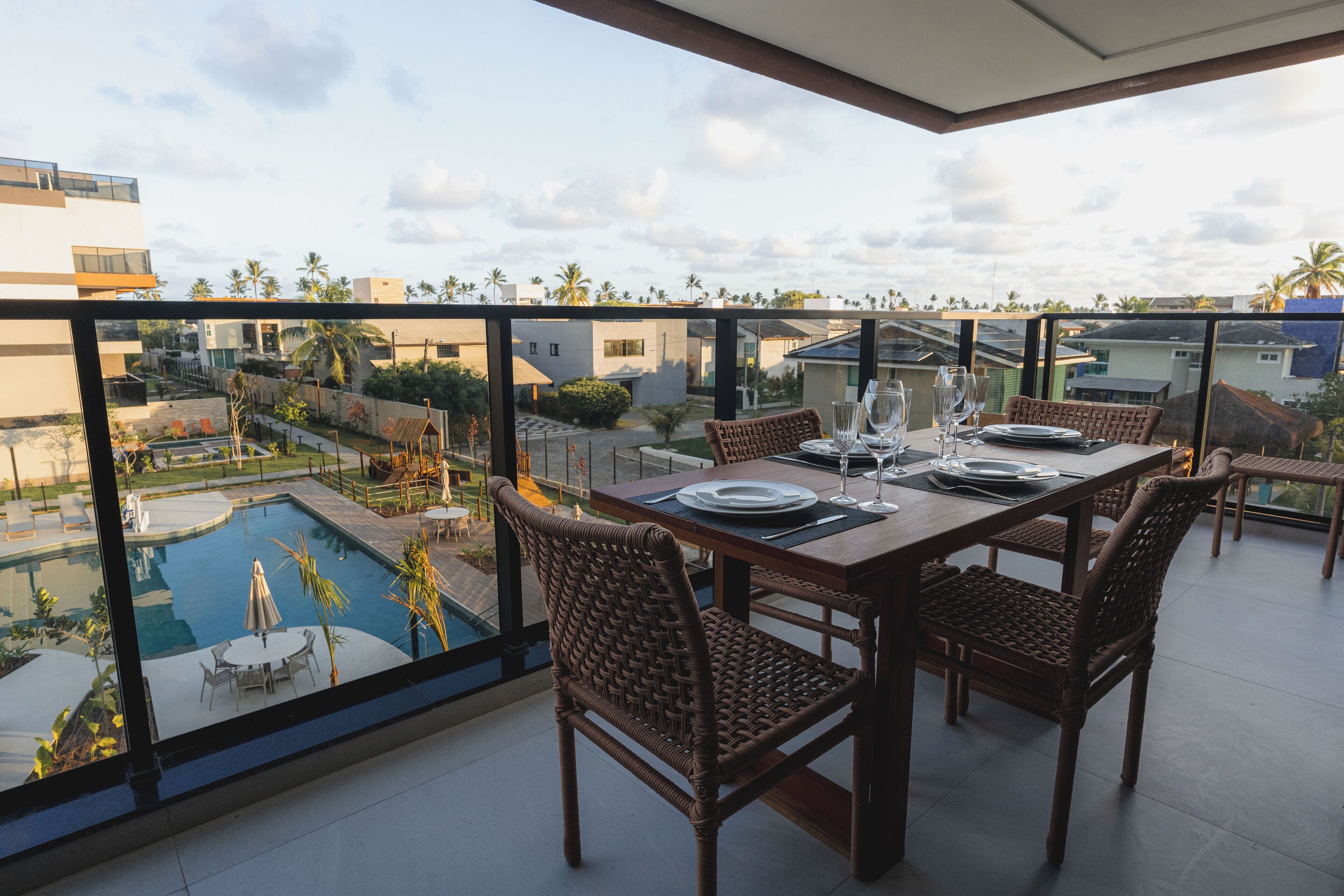 A dining area with a table set for four, overlooking a swimming pool and a residential area.