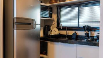 Una cocina moderna con electrodomésticos de acero inoxidable, horno empotrado y ventana con persianas.