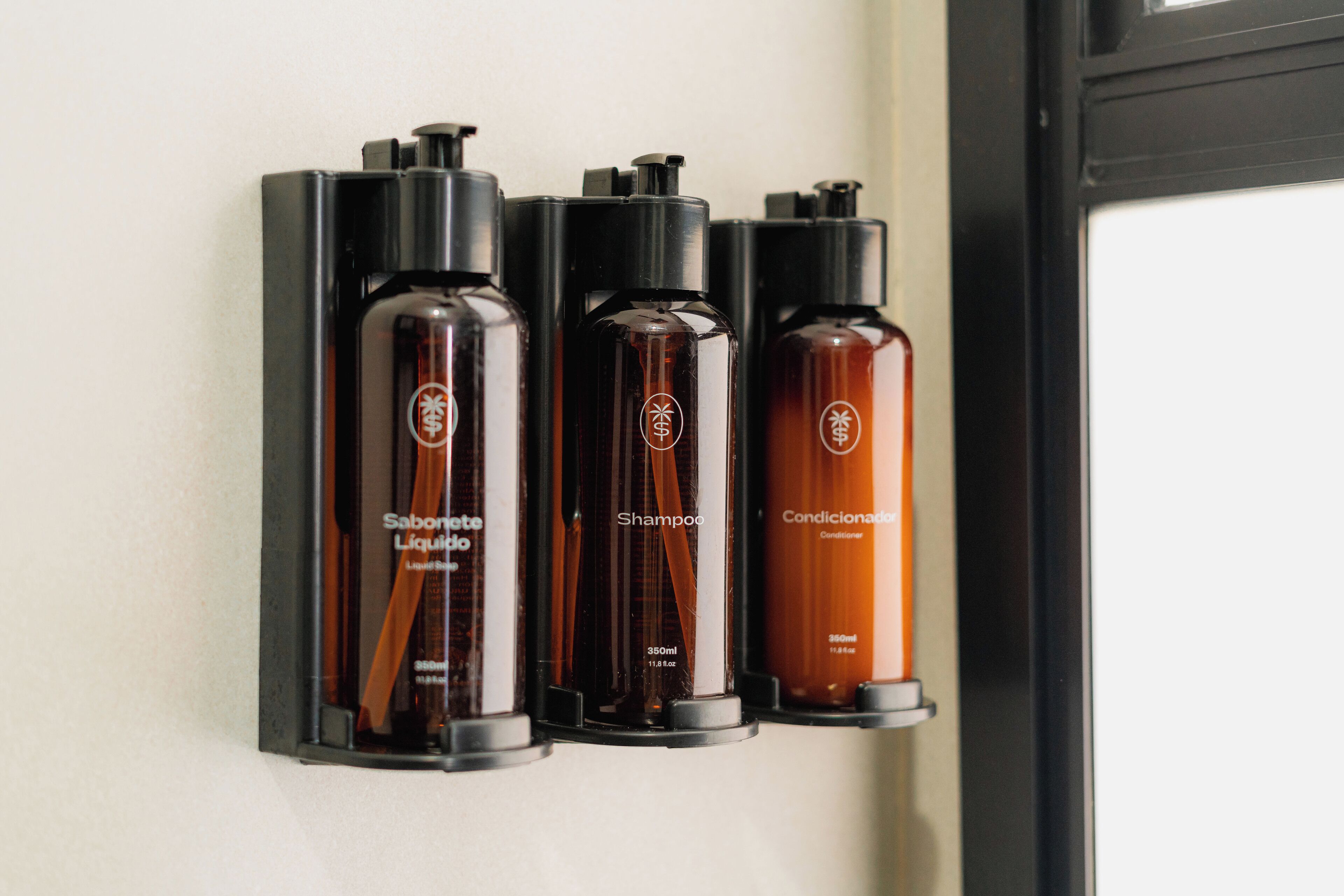 Three bottles of hair care products on a black wall-mounted shelf.