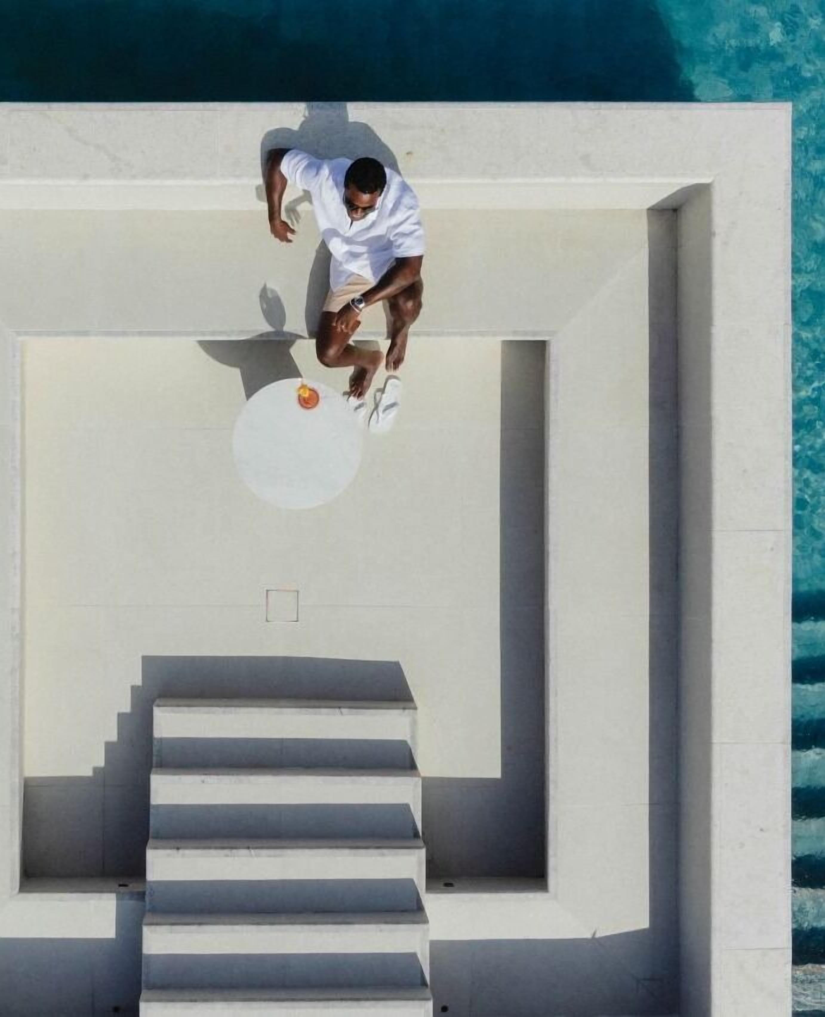 Ein Mann springt von einer weißen Treppe in einen Pool.