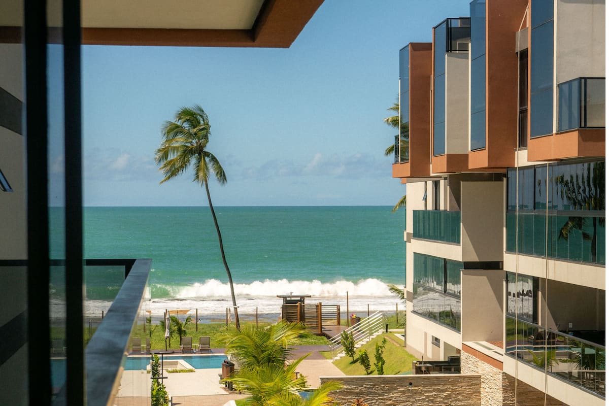 Un hotel moderno con piscina, palmeras y vistas al océano.