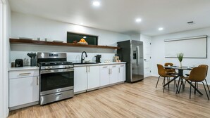 Una cocina moderna con armarios blancos, electrodomésticos de acero inoxidable y suelo de madera.