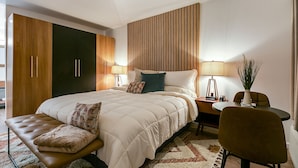 A modern hotel room with a large bed, a bench, a desk, and a chair. - Spacious King Room with Modern Comforts – Ideal for Relaxing Getaways! (San Angelo)