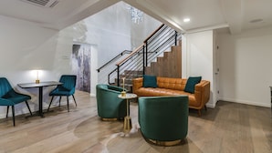 A modern living room with a staircase, a leather sofa, teal armchairs, and a small table with a lamp. - Spacious King Room with Modern Comforts – Ideal for Relaxing Getaways! (San Angelo)