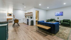 Ein modernes Wohnzimmer mit einem blauen Sofa, einer hölzernen Bank und einem Essbereich mit Tisch und Stühlen.