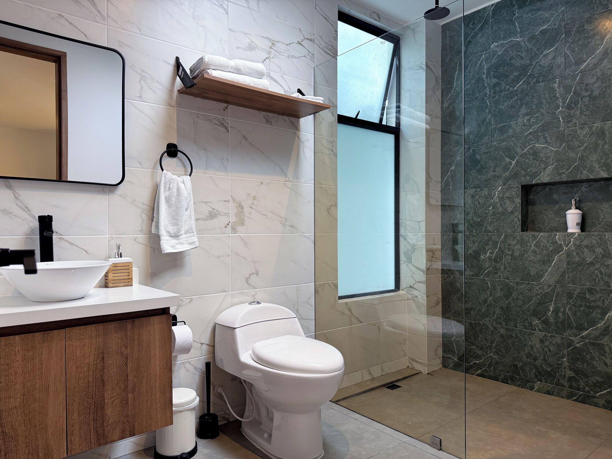 Une salle de bain moderne avec un meuble-lavabo en marbre, des toilettes et un espace douche.